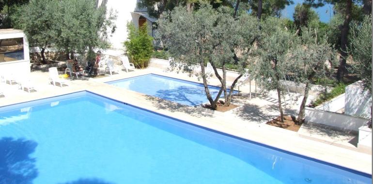 Piscina con vista mare, circondata da alberi e natura.