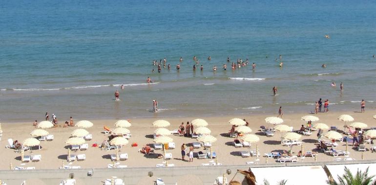 Spiaggia affollata con ombrelloni e bagnanti nel mare.